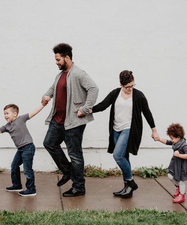 family walking on sidewalk holding hands