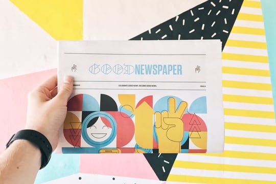 hand holding newspaper with geometric shapes